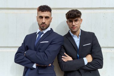 Two hispanic men business workers standing with arms crossed gesture over isolated white background