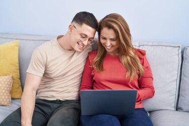 Man and woman mother and son using laptop sitting on sofa at home