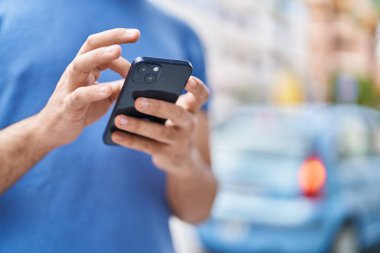 Young latin man using smartphone at street