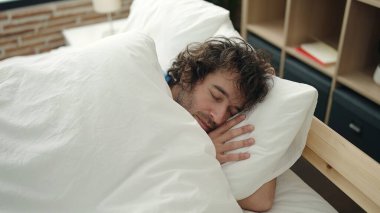 Genç İspanyol adam yatakta uzanıp yatak odasında uyuyor.