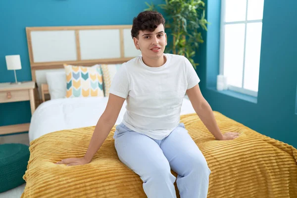 Non binary man smiling confident sitting on bed at bedroom