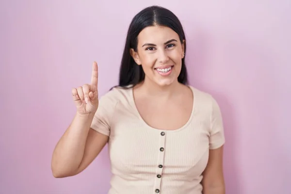 Young Hispanic Woman Standing Pink Background Showing Pointing Finger Number — Φωτογραφία Αρχείου