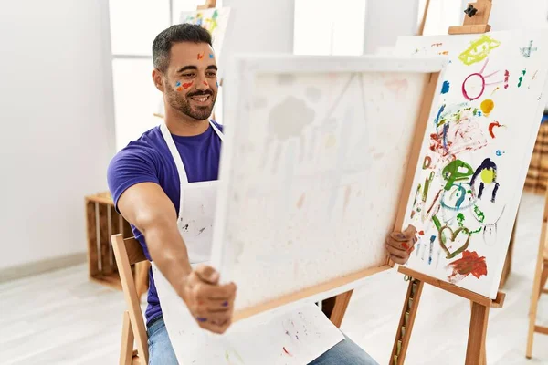 Młody Hiszpan Uśmiecha Się Pewnie Trzymając Płótno Pracowni Artystycznej — Zdjęcie stockowe