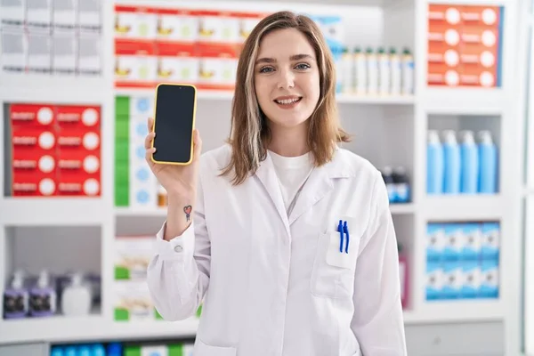 Blonde Caucasian Woman Working Pharmacy Drugstore Showing Smartphone Screen Looking — Stockfoto