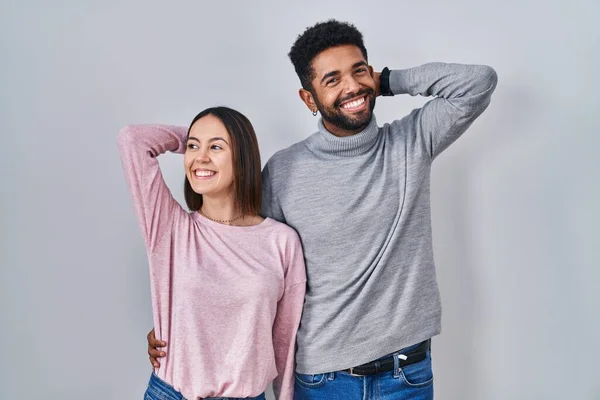 Young Hispanic Couple Standing Together Relaxing Stretching Arms Hands Head — Stockfoto