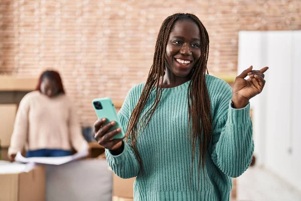 Yeni Evinde Akıllı Telefon Kullanan Afrikalı Bir Kadın Gülümsüyor — Stok fotoğraf