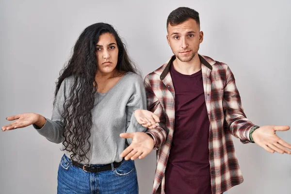 Young Hispanic Couple Standing White Background Clueless Confused Open Arms — Stock fotografie