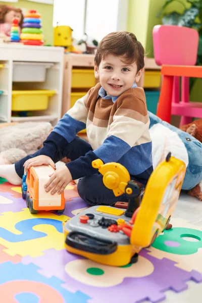 愛らしいヒスパニック男の子遊びますともにトラックおもちゃ座っています床に幼稚園 — ストック写真