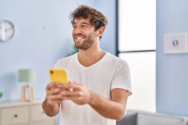 Young man smiling confident using smartphone at home