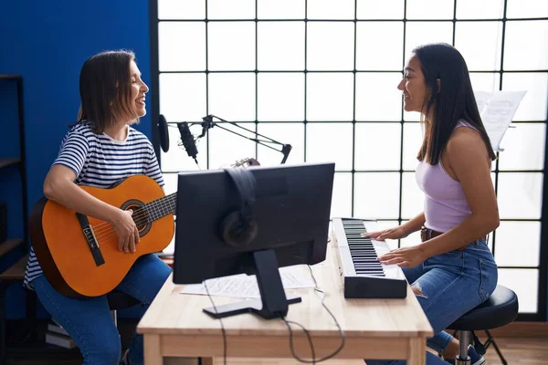 Two women musicians playing classical guitar and piano at music studio