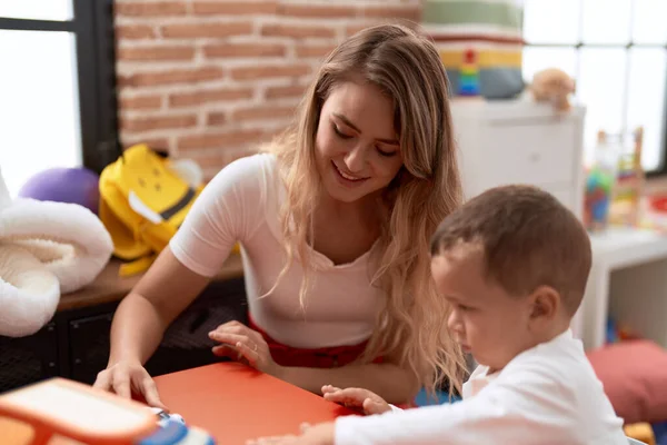 教師と幼児遊び車おもちゃでテーブルの上に座って幼稚園 — ストック写真