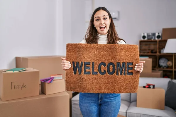 Young Hispanic Woman Holding Welcome Doormat New Home Celebrating Crazy — Zdjęcie stockowe
