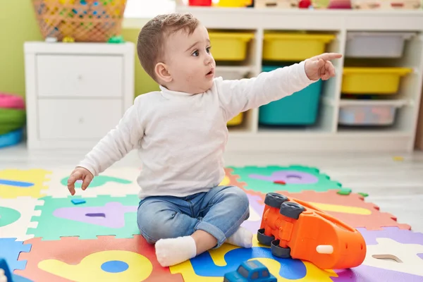 可愛い白人の赤ん坊遊びとともにトラックおもちゃで床に座って幼稚園 — ストック写真