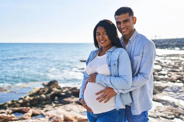 Young Latin Couple Expecting Baby Hugging Each Other Standing Seaside — ストック写真