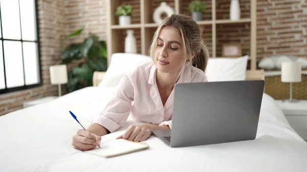 Young Blonde Woman Using Laptop Writing Notebook Bedroom — Stockfoto
