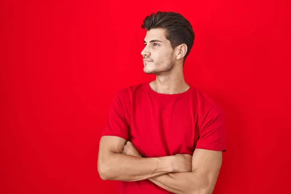 Young Hispanic Man Standing Red Background Looking Side Arms Crossed — Stockfoto