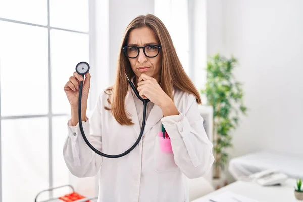 Young Woman Wearing Doctor Uniform Holding Stethoscope Serious Face Thinking —  Fotos de Stock