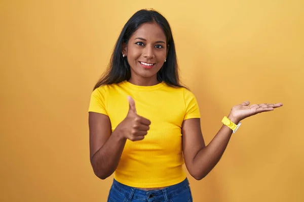 Young Indian Woman Standing Yellow Background Showing Palm Hand Doing — Stock Photo, Image