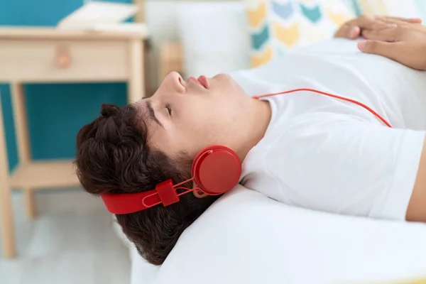 Non binary man listening to music relaxed on bed at bedroom