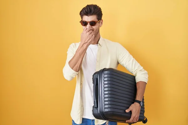 Young Hispanic Man Holding Suitcase Going Summer Vacation Smelling Something — Stock fotografie