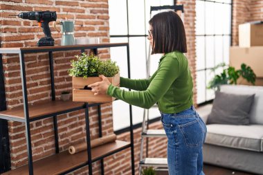 Genç, güzel İspanyol kadın yeni evinde tahta saksı tutuyor.