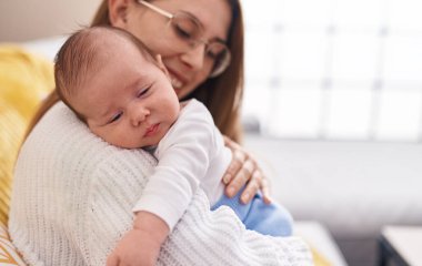 Mother and son hugging each other sitting on sofa at home