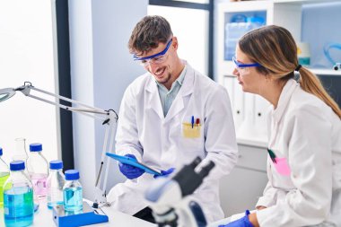 Genç erkek ve kadın bilim adamları laboratuarda çalışan touchpad 'i kullanıyorlar.