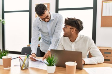 İki İspanyol iş adamı ofiste çalışırken gülümsüyor.