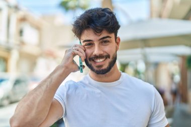 Genç İspanyol adam gülümsüyor. Kendine güveniyor. Sokakta akıllı telefondan konuşuyor.