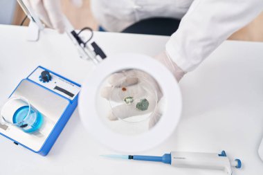 Young latin man scientist looking sample using loupe at laboratory