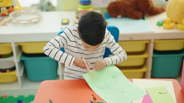 Anaokulunda kağıt kesen sevimli İspanyol çocuk.
