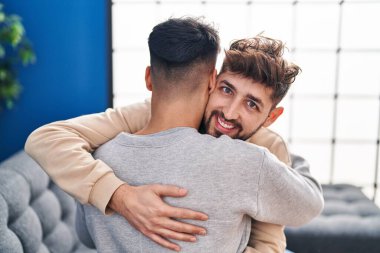 Young couple hugging each other sitting on sofa at home