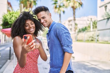Man and woman couple smiling confident using smartphone at street
