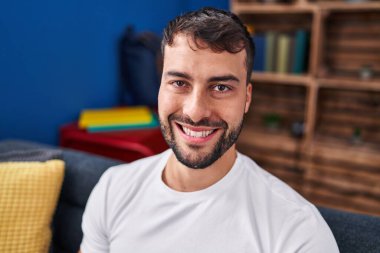 Evdeki kanepede kendinden emin gülümseyen İspanyol genç adam.