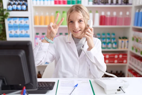 Young Caucasian Woman Working Pharmacy Drugstore Speaking Telephone Smiling Looking — Zdjęcie stockowe