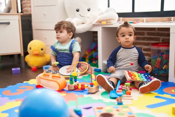 木琴とタンバリンを演奏する2人の子供が幼稚園で床に座っています — ストック写真