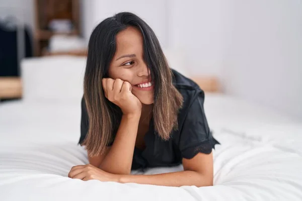 Young hispanic woman smiling confident lying on bed at bedroom