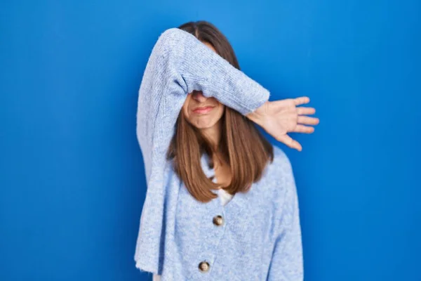 Young Woman Standing Blue Background Covering Eyes Arm Looking Serious — Stockfoto
