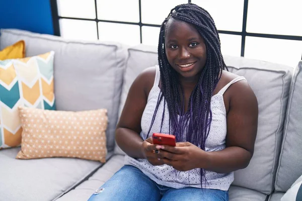 非洲裔美国妇女坐在家里沙发上用智能手机 — 图库照片