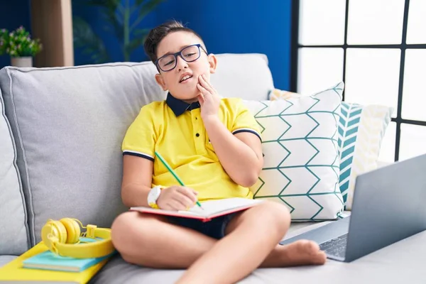Young Hispanic Kid Doing Homework Sitting Sofa Touching Mouth Hand — Stok fotoğraf