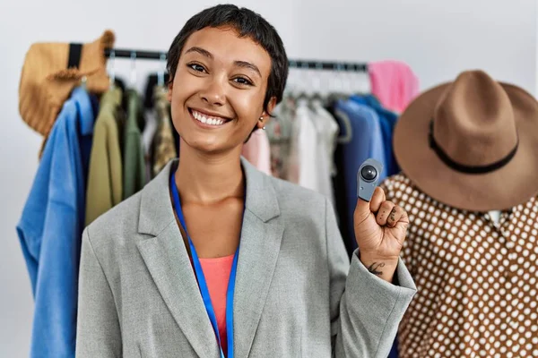 Young Hispanic Woman Shopkeeper Smiling Confident Holding Security Alarm Clothing — Fotografia de Stock