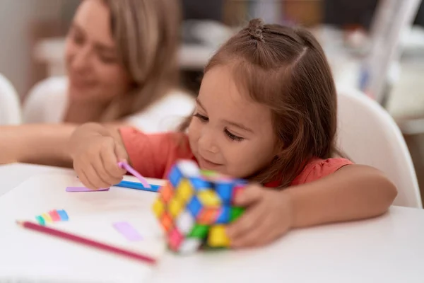 Teacher Toddler Sitting Table Holding Rubik Cube Kindergarten — Zdjęcie stockowe