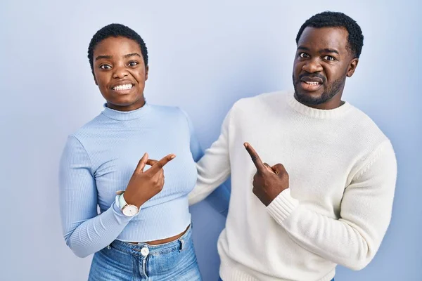 一对年轻的非洲裔美国夫妇站在蓝色的背景上 用食指把焦虑和紧张抛在一边 忧心忡忡 满脸诧异 — 图库照片
