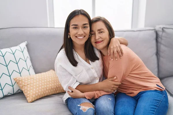 Two women mother and daughter sitting on sofa together at home