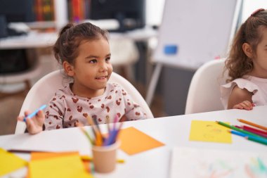 Two kids preschool students sitting on table drawing on paper at classroom