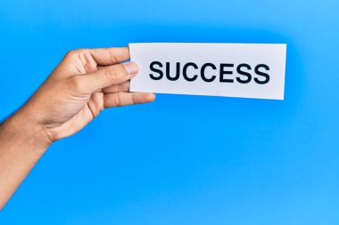 Hand of caucasian man holding paper with success word over isolated blue background