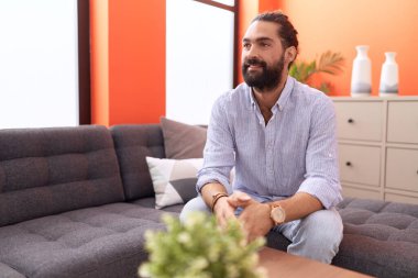 Genç İspanyol adam, ellerini başının üstüne koyup evinde kanepede oturarak rahatladı.