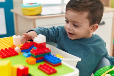 Anaokulundaki masada oturan, inşaat bloklarıyla oynayan sevimli İspanyol çocuk.