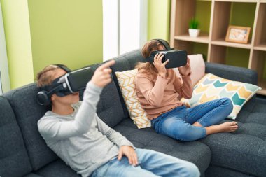 Two kids playing video game using virtual reality glasses at home