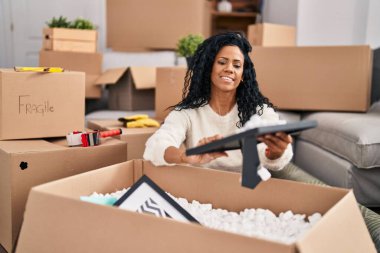 Afrika kökenli Amerikalı bir kadın yeni evindeki karton kutuları açıyor.